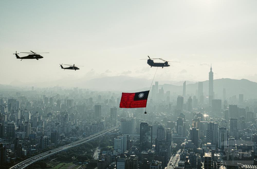 陸航UH-60M直升機及CH-47SD直升機懸掛巨幅國旗飛越臺北市上空。（軍聞社記者陳軍均攝）