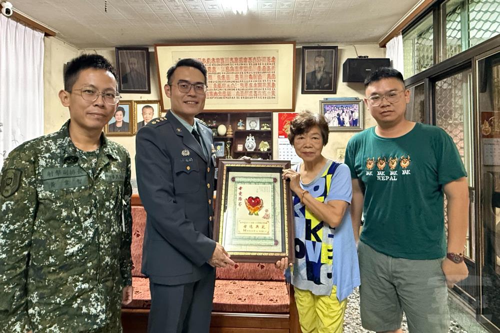 政戰主任張上校代表旅長蔡上校，赴榮獲單位模範母親府邸致贈賀屏。（陸軍第十軍團提供）