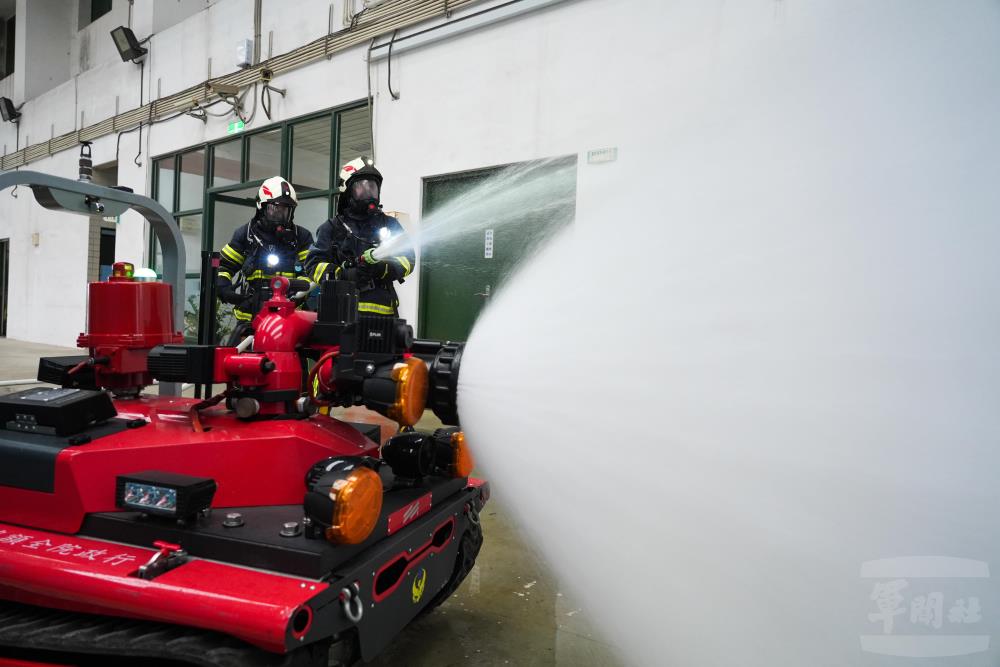 救災機器人完成火場探測後與消防員協力滅火。（軍聞社記者陳傳奇攝）