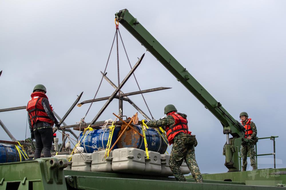 官兵運用浮門橋車吊臂將阻絕設施置於載臺上。（軍聞社記者王進福攝）