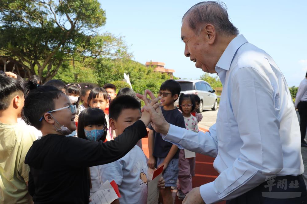 李榮譽理事長關心學校教育環境，並與學童握手擊掌。（軍友社提供）