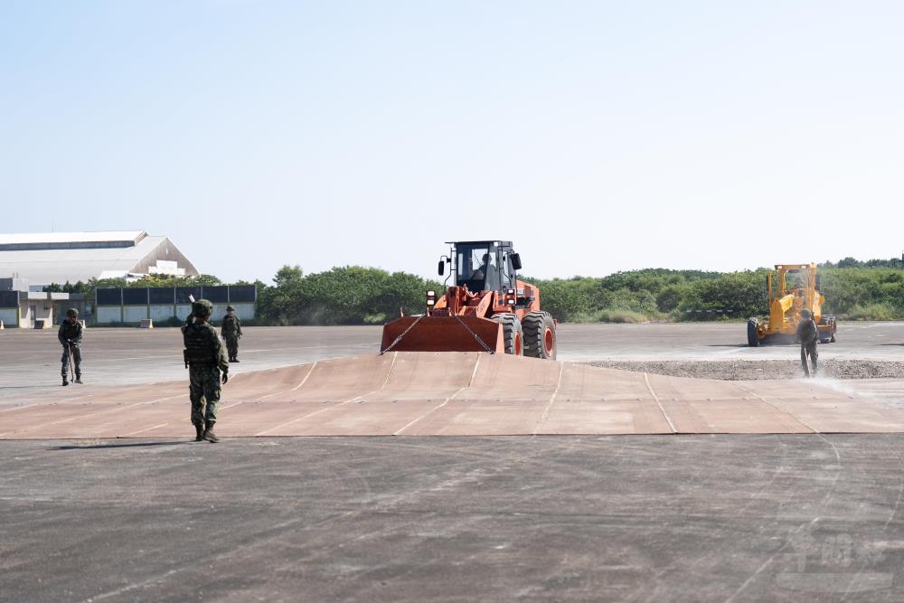 官兵將玻璃纖維墊拖曳至已整平的彈坑上方鋪設。（軍聞社記者林庭暉攝）