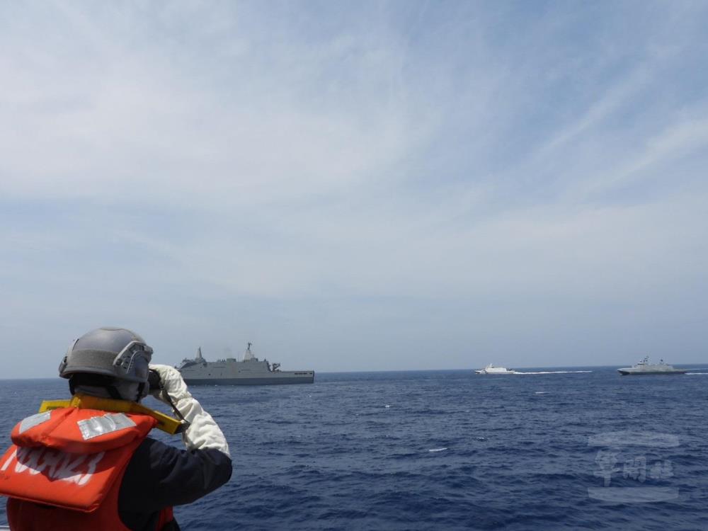 玉山軍艦模擬載運重要物資商船，在海軍及海巡兵力協同下執行護航任務。（海軍司令部提供）