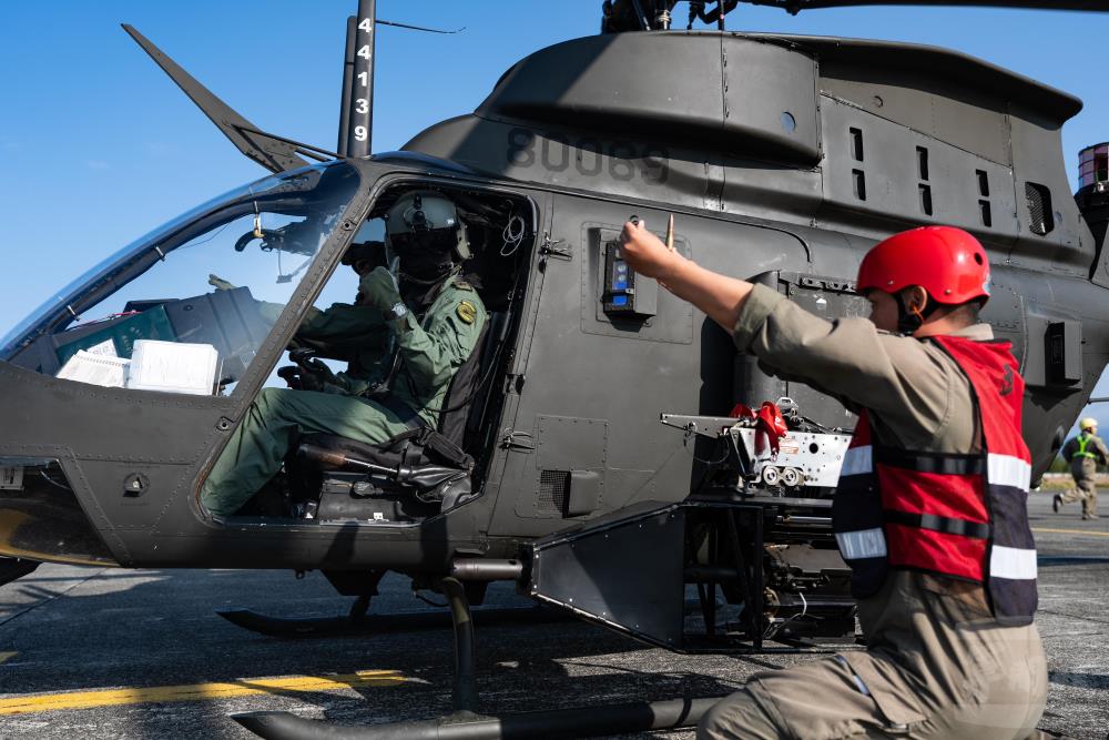 在震耳欲聾的旋翼與引擎聲中，飛官與武器組以手勢互相溝通。（軍聞社記者林庭暉攝）