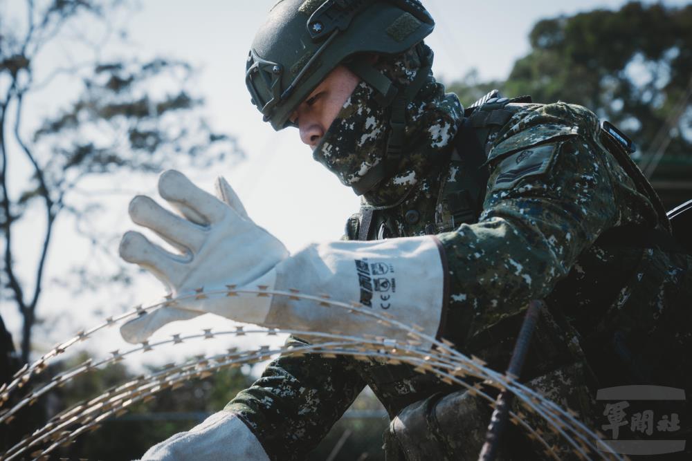 官兵布設蛇腹型鐵絲網。（軍聞社記者文仁攝）