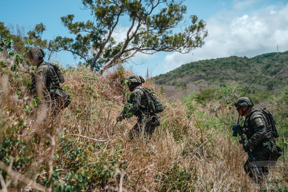 訓場模擬戰場實景，官兵穿梭於草叢及低窪處，進行戰術運動。（軍聞社記者林庭暉攝）