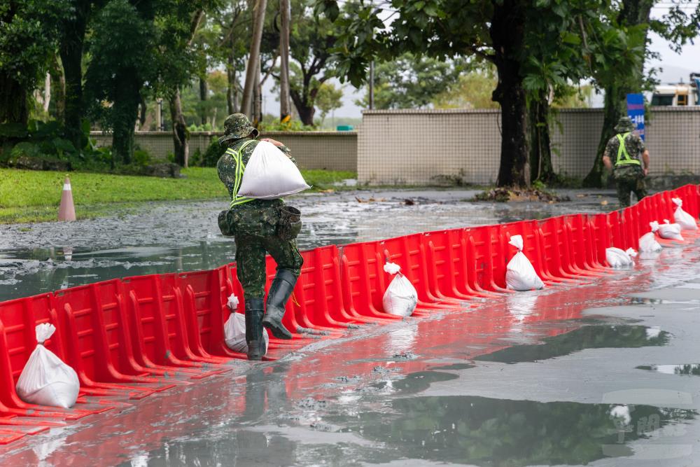 運用沙包加固導流擋水板。（軍聞社記者蔡枋澐攝）