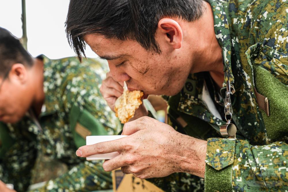 官兵不顧身上仍有淤泥用餐，全力投入協助恢復家園。（軍聞社記者劉哲宇攝）