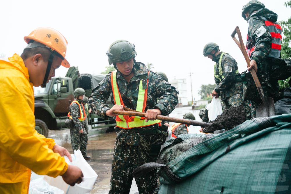 官兵在雨中進行沙包裝袋作業。（軍聞社記者林庭暉攝）
