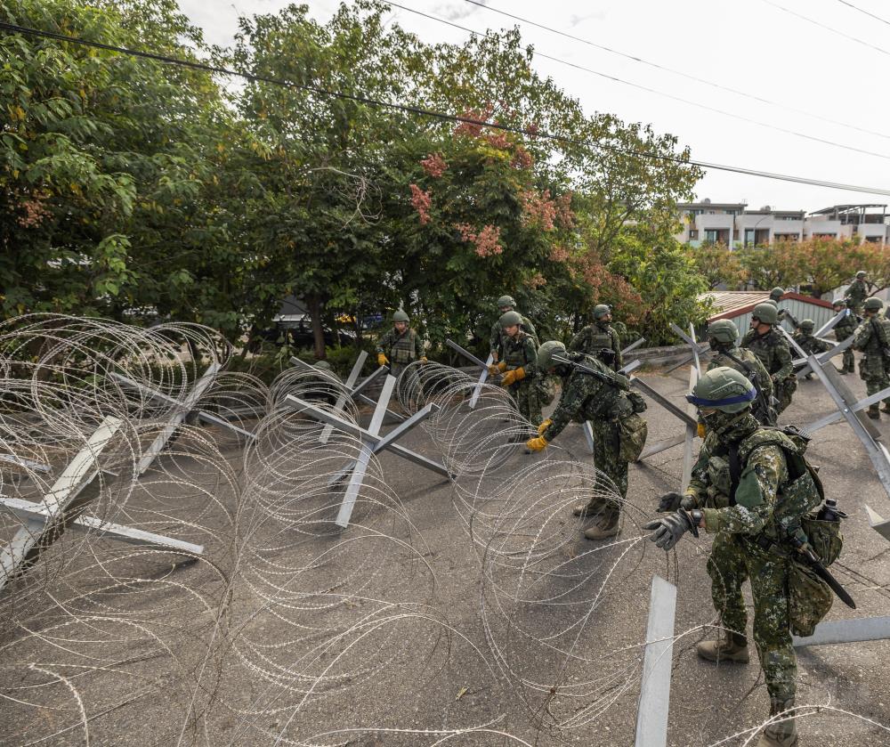 官兵迅速展開蛇腹型鐵絲網，於主要道路交會處建立阻絕設施。（軍聞社記者莊家豪攝）