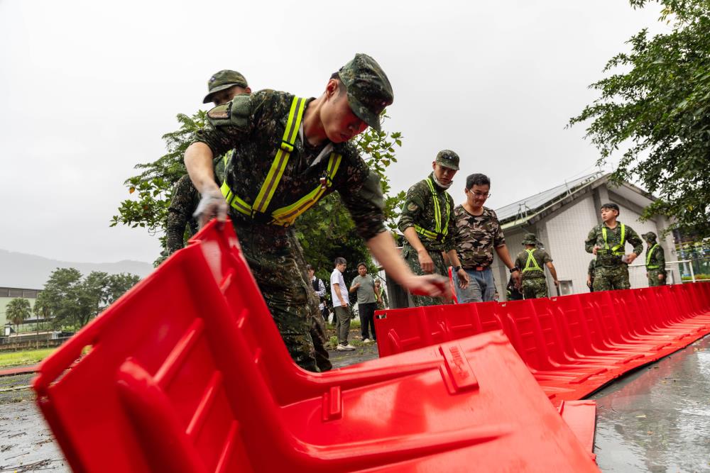 官兵協助校園設置導引水流擋水板。（軍聞社記者蔡枋澐攝）