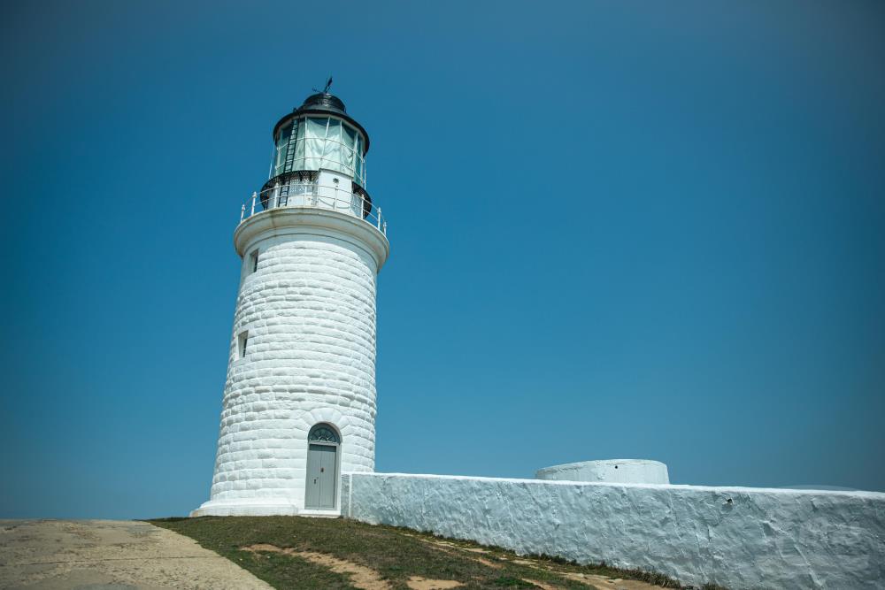 燈塔旁築有一道長達數公尺的白色矮牆，早期為抵禦強風、避免煤油燈被吹熄所建。（軍聞社記者邱奕菖攝）