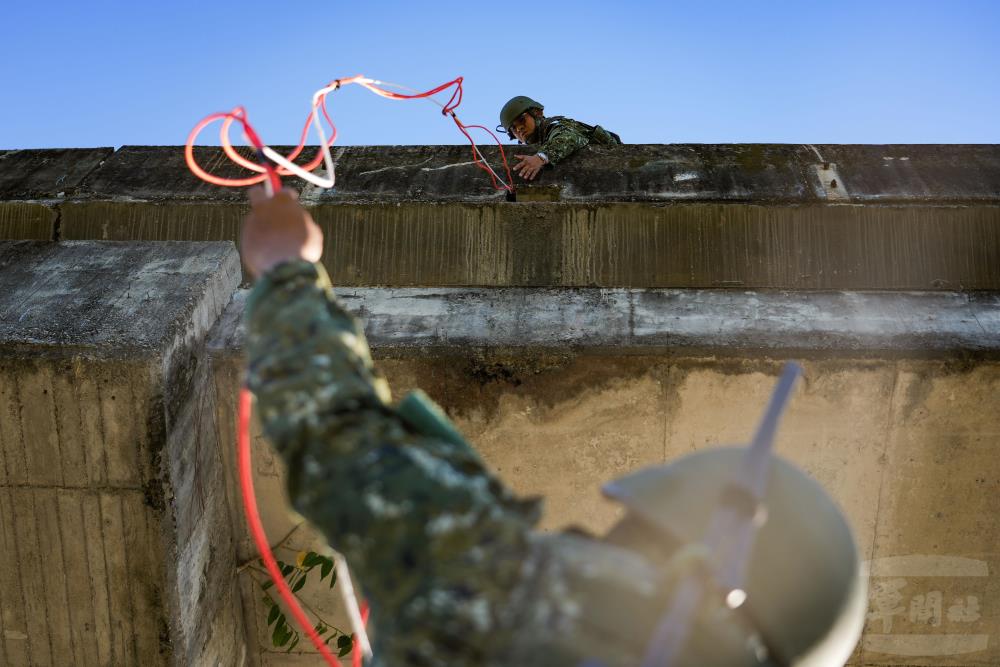 官兵將導爆索垂放至橋腳位置，以利接上爆藥。（軍聞社記者黃劭恩攝）