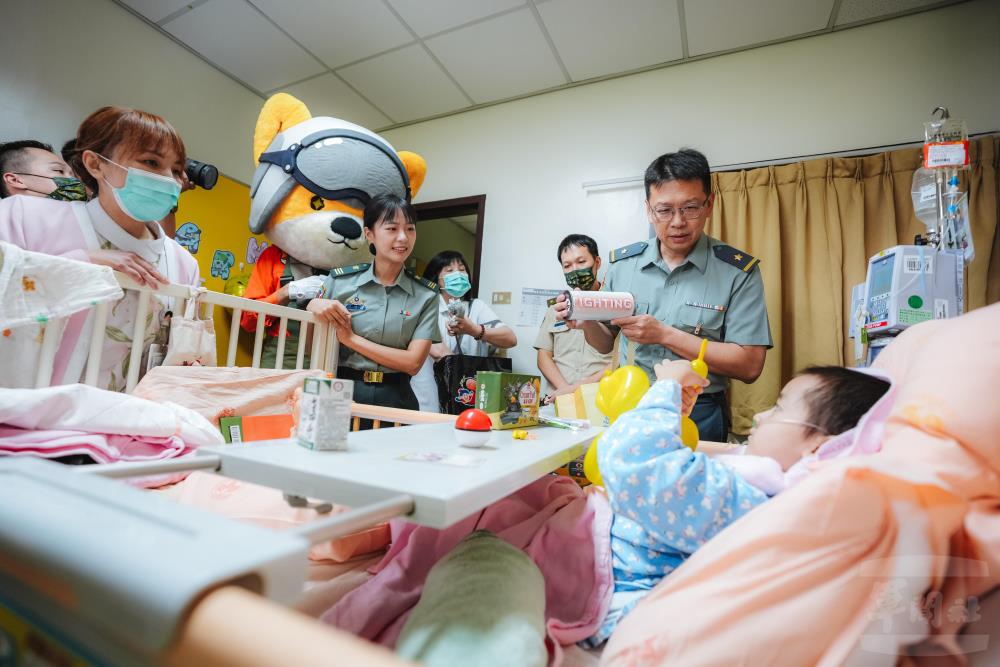 文宣心戰處王處長偕同三軍吉祥物「柴寶」，向病童展示「Fighting」紀念T恤，鼓勵病童勇敢面對治療，傳遞國軍關懷與祝福。（軍聞社記者劉哲宇攝）